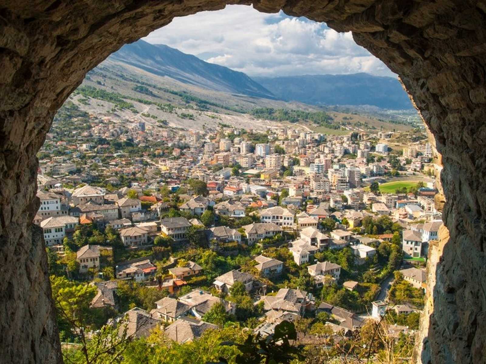 גשר אבן עות'מאני עתיק באלבניה עם ילדים מעל נהר צלול ונוף כפרי ירוק