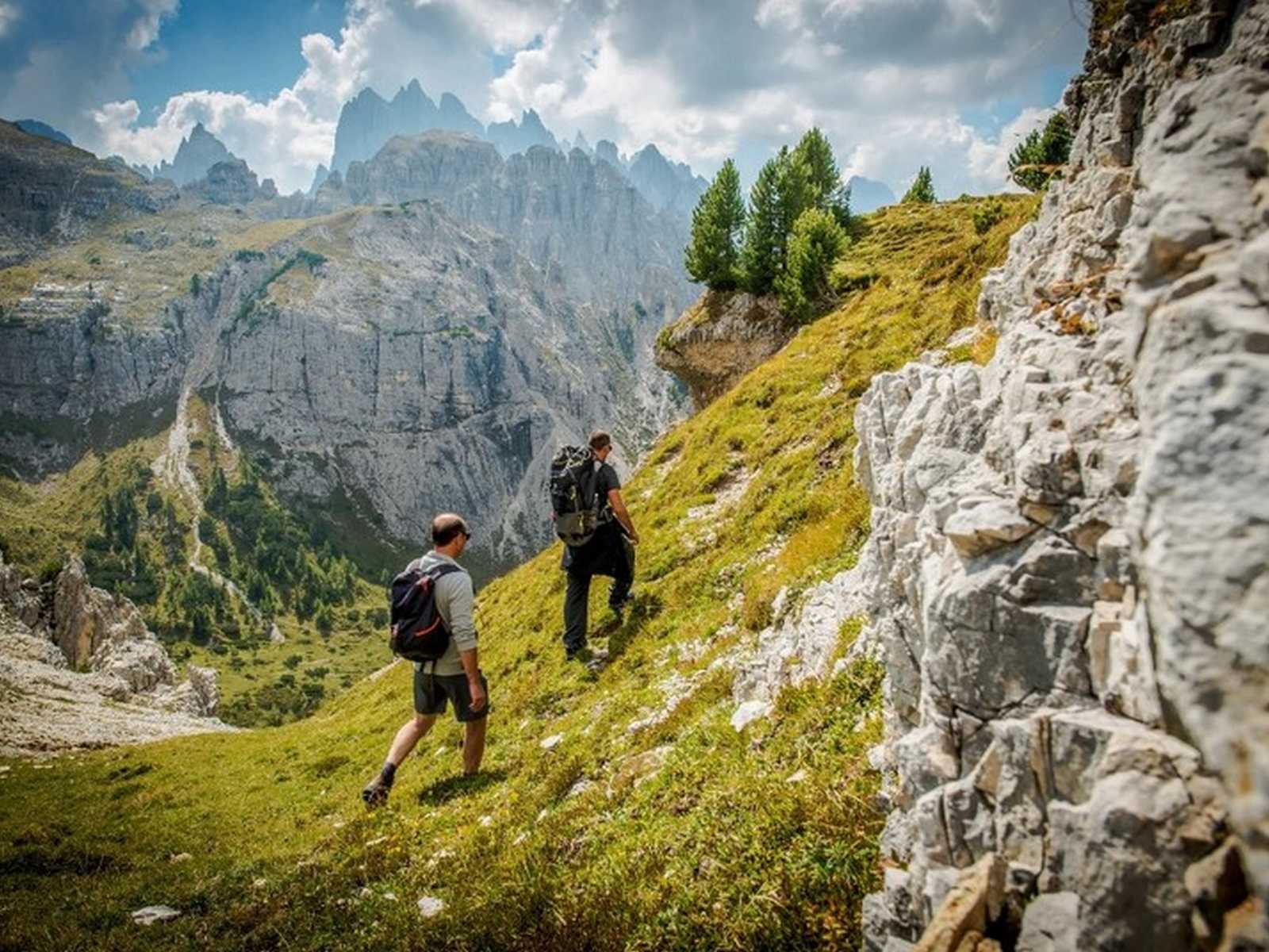 מטיילים בשביל הררי עם תצפית פנורמית על הרי דולומיטים