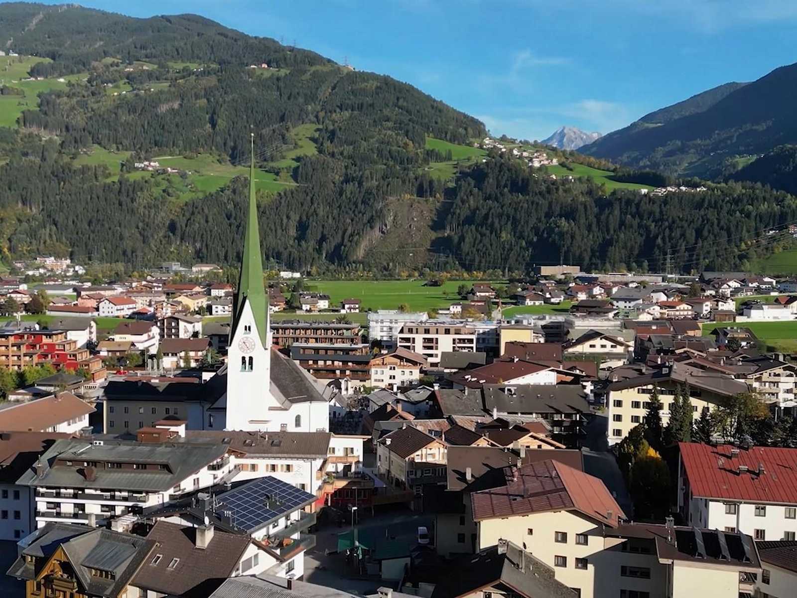 עיירה אלפינית מסורתית עם צריח כנסייה והרים מסביב בחבל טירול