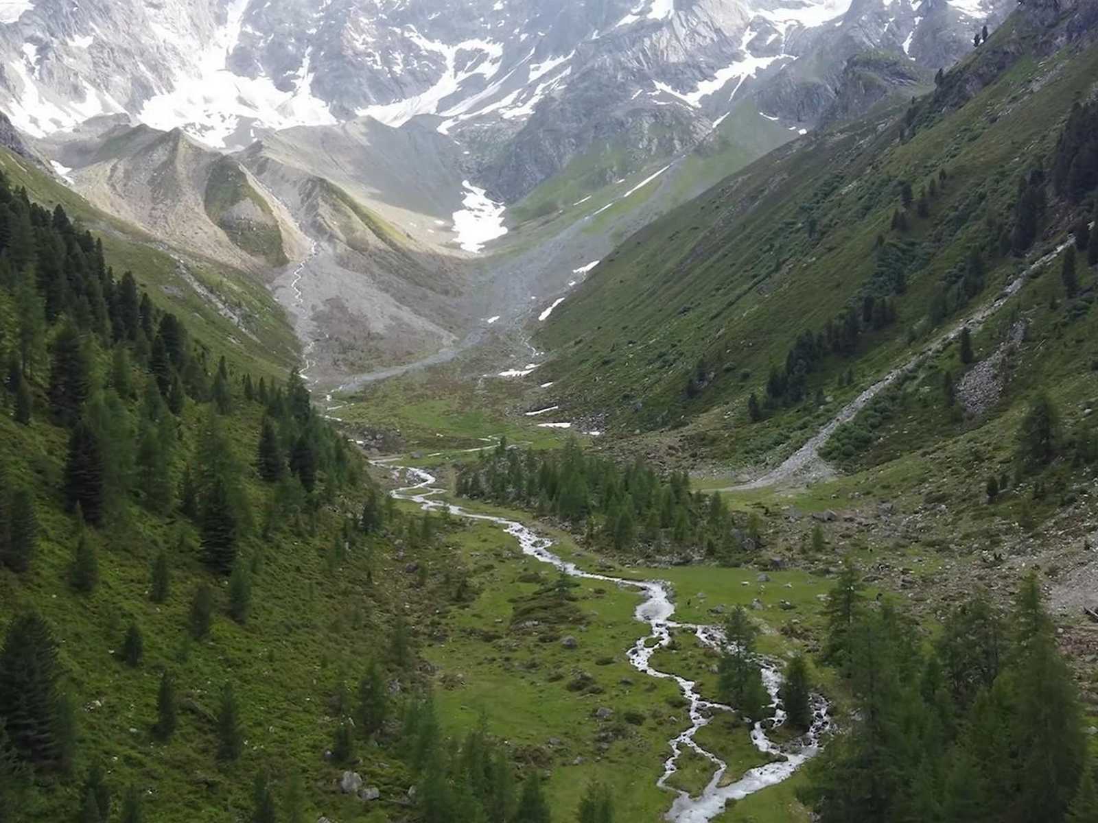 עמק הררי רחב עם נהר מתפתל ונופים דרמטיים בחבל טירול