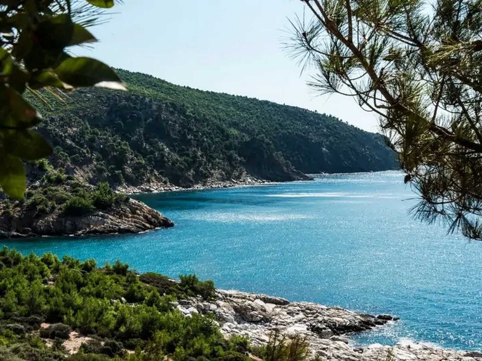 צפון יוון – נוף טבעי של מפרץ שקט עם מים צלולים והרים ברקע